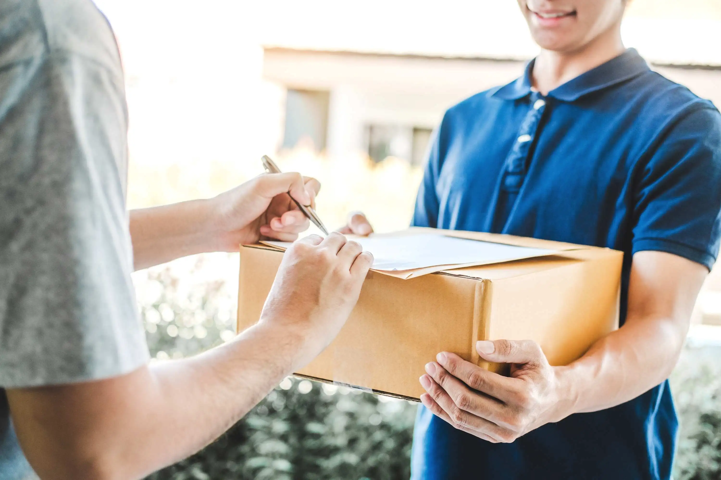A courier handing a parcel over to a customer and signing for the delivery